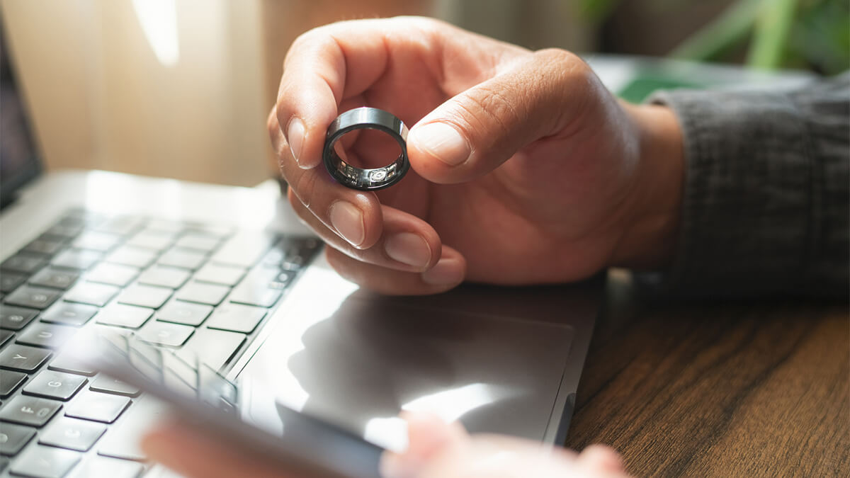 Person holding smart ring and smartphone
