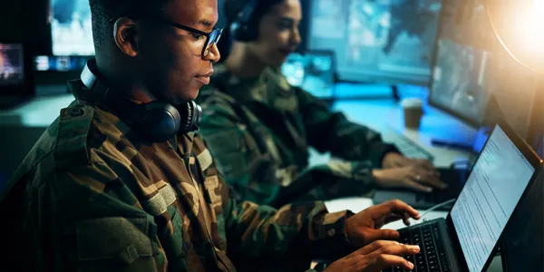 Military control room, computer and soldier at desk, typing code and tech for communication army office.