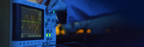 Close up of hand turning dial of modern electronic oscilloscope. Electronic engineer using EMI receiver during experiments or testing equipment in laboratory
