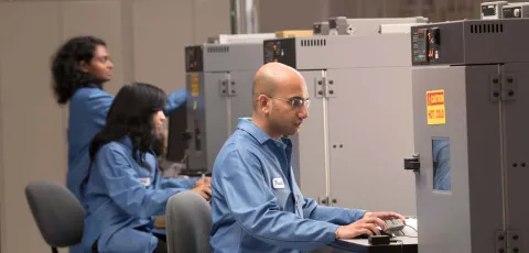 Sitime workers in laboratory, wearing blue lab coats